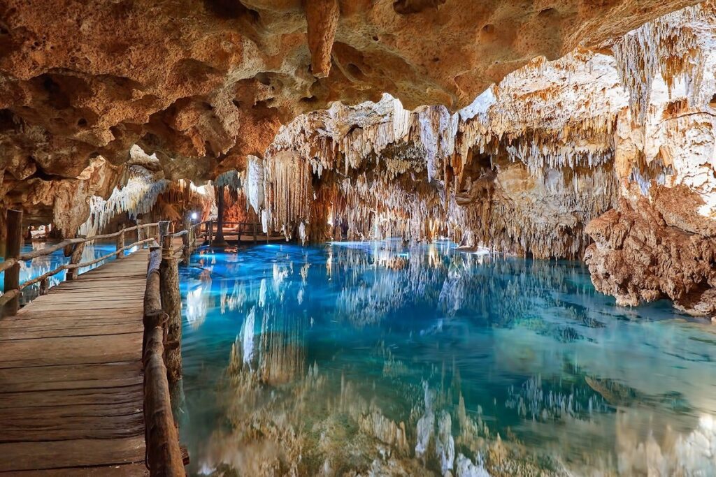 Cenote mit tuerkisblauem Wasser und Tropfsteinen beim Ausflug nach Coba und Tulum